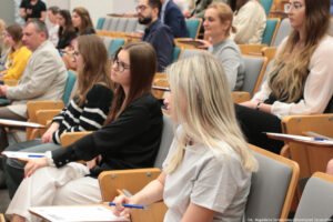 Dyktando Uniwersyteckie 2025. Sala wykładowa. Ujęcie bokiem na uczestników konkursu.